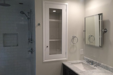 This is an example of a small transitional master bathroom in DC Metro with furniture-like cabinets, dark wood cabinets, a curbless shower, gray tile, stone tile, marble floors, an undermount sink and marble benchtops.
