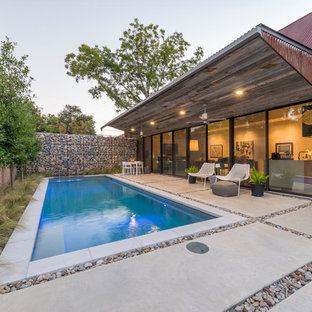 Kleines Industrial Sportbecken hinter dem Haus in rechteckiger Form mit Wasserspiel und Betonplatten in Dallas