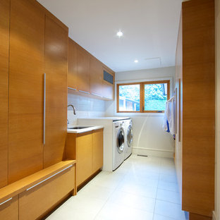 Ejemplo de cuarto de lavado de galera, actual, grande, con fregadero bajoencimera, armarios con paneles lisos, puertas de armario de madera oscura, paredes blancas, lavadora y secadora juntas, encimera de cuarzo compacto, suelo de baldosas de porcelana y suelo blanco