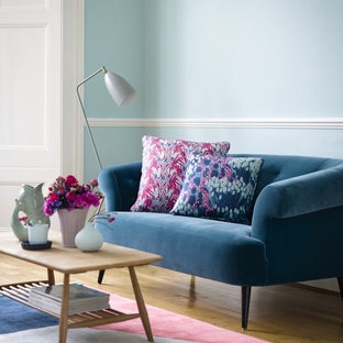 This is an example of a small midcentury living room in London with blue walls, light hardwood flooring, no fireplace and no tv.