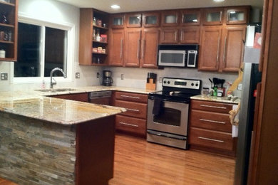 Eat-in kitchen - mid-sized transitional u-shaped light wood floor eat-in kitchen idea in Detroit with an undermount sink, flat-panel cabinets, medium tone wood cabinets, granite countertops, white backsplash, stone tile backsplash and stainless steel appliances