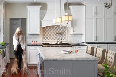 Inspiration for a large transitional l-shaped medium tone wood floor and brown floor eat-in kitchen remodel in Atlanta with a farmhouse sink, flat-panel cabinets, gray cabinets, marble countertops, gray backsplash, porcelain backsplash, stainless steel appliances and an island