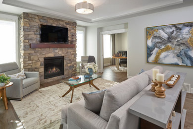 Living room - mid-sized contemporary open concept medium tone wood floor living room idea in Edmonton with gray walls, a standard fireplace, a stone fireplace and a wall-mounted tv