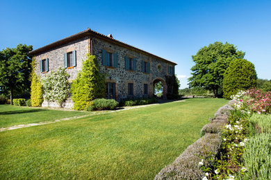 Esempio della villa piccola multicolore rustica a due piani con rivestimento in pietra, tetto a capanna e copertura in tegole