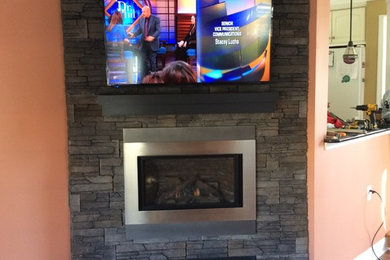 Large enclosed games room in Philadelphia with orange walls, medium hardwood flooring, a corner fireplace and a wall mounted tv.