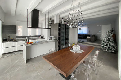 Foto di una sala da pranzo aperta verso la cucina contemporanea con pavimento in gres porcellanato, pavimento grigio, travi a vista e pannellatura