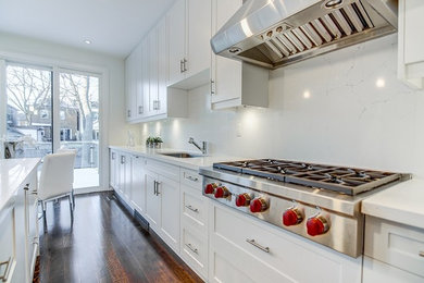 Photo of a contemporary eat-in kitchen in Toronto with white cabinets, quartz benchtops, white splashback, stone slab splashback and with island.