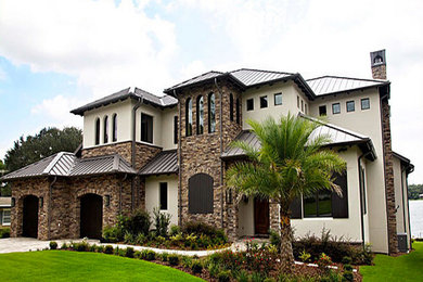 This is an example of a mid-sized mediterranean two-storey beige house exterior in Orlando with mixed siding, a hip roof and a metal roof.