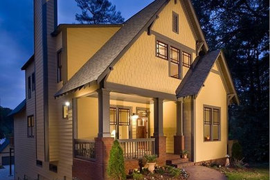 Diseño de fachada de casa amarilla de estilo americano de tamaño medio de tres plantas con revestimiento de aglomerado de cemento, tejado a dos aguas y tejado de teja de madera