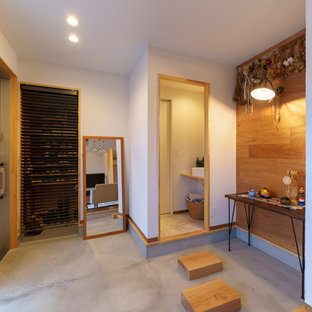 他の地域の小さい引き戸アジアンスタイルのおしゃれな玄関ホール (茶色い床、白い壁、コンクリートの床、金属製ドア) の写真