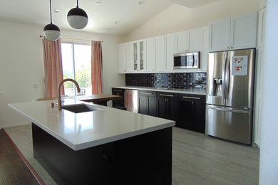 Open concept kitchen - large modern l-shaped laminate floor and beige floor open concept kitchen idea in Los Angeles with an undermount sink, shaker cabinets, white cabinets, quartz countertops, black backsplash, subway tile backsplash, stainless steel appliances, an island and white countertops
