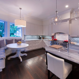 На фото: большая п-образная кухня в современном стиле с кладовкой, синим фартуком, техникой из нержавеющей стали, темным паркетным полом и островом с