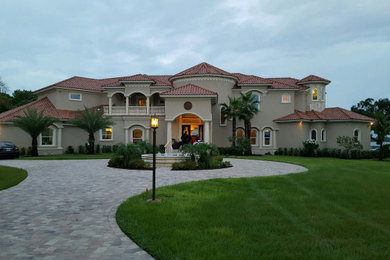 Example of a huge tuscan beige two-story stucco house exterior design in Tampa with a hip roof and a tile roof
