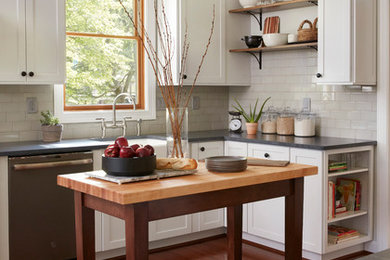 Design ideas for a country l-shaped kitchen in Baltimore with a farmhouse sink, shaker cabinets, white cabinets, white splashback, subway tile splashback, stainless steel appliances, dark hardwood floors, with island, grey benchtop and soapstone benchtops.