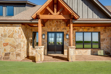 Mid-sized elegant brown two-story stone and board and batten exterior home photo in Dallas with a shingle roof and a brown roof