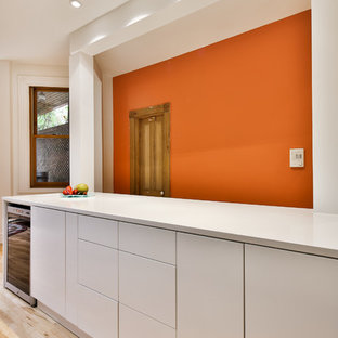 Zweizeilige, Mittelgroße Moderne Küche mit Vorratsschrank, flächenbündigen Schrankfronten, gelben Schränken, Glas-Arbeitsplatte, Rückwand aus Zementfliesen, hellem Holzboden und Kücheninsel in Montreal