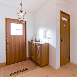 他の地域の片開きドアカントリー風おしゃれな玄関 (白い壁、テラコッタタイルの床、木目調のドア、オレンジの床) の写真