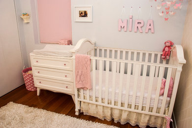 Nursery - small transitional girl medium tone wood floor nursery idea in Chicago with gray walls