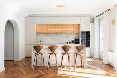 Idée de décoration pour une cuisine américaine linéaire, encastrable, haussmannienne et beige et blanche nordique de taille moyenne avec un évier intégré, un placard à porte affleurante, des portes de placard beiges, un plan de travail en quartz, une crédence blanche, une crédence en quartz modifié, un sol en bois brun, îlot, un plan de travail blanc et un plafond en bois.