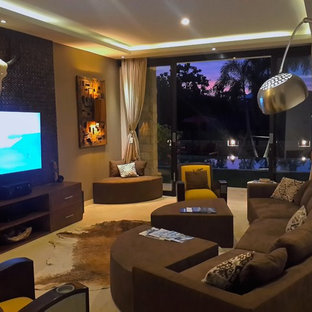 Photo of a large world-inspired enclosed home cinema with brown walls, limestone flooring and a wall mounted tv.