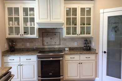 Inspiration for a mid-sized contemporary galley light wood floor eat-in kitchen remodel in Raleigh with an undermount sink, raised-panel cabinets, white cabinets, granite countertops, beige backsplash, stone tile backsplash, stainless steel appliances and an island