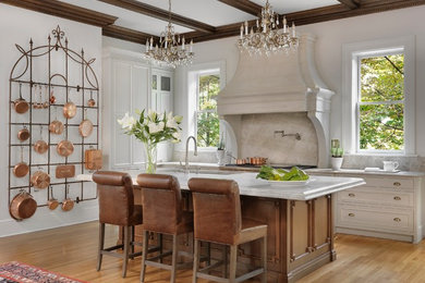 Inspiration for a traditional galley kitchen in St Louis with an undermount sink, recessed-panel cabinets, medium wood cabinets, white splashback, stone slab splashback, stainless steel appliances, medium hardwood floors, with island, brown floor and white benchtop.