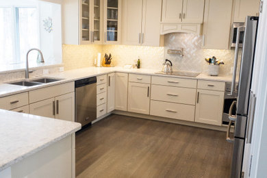 Mid-sized transitional u-shaped medium tone wood floor and gray floor kitchen photo in Other with an undermount sink, shaker cabinets, white cabinets, quartz countertops, white backsplash, subway tile backsplash, stainless steel appliances, a peninsula and gray countertops