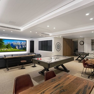 Huge trendy carpeted and beige floor home theater photo in Central Coast with white walls and a wall-mounted tv