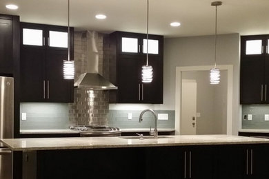 Inspiration for a large modern galley dark wood floor and brown floor open concept kitchen remodel in Other with an undermount sink, shaker cabinets, dark wood cabinets, granite countertops, blue backsplash, glass tile backsplash, stainless steel appliances and an island