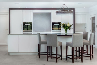 This is an example of a contemporary kitchen in Buckinghamshire with white cabinets, quartzite benchtops, stone slab splashback and porcelain floors.