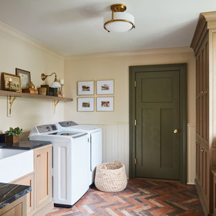 Inspiration för stora u-formade svart grovkök, med en rustik diskho, skåp i shakerstil, bänkskiva i kvartsit, svart stänkskydd, beige väggar, klinkergolv i porslin, en tvättmaskin och torktumlare bredvid varandra, flerfärgat golv och skåp i ljust trä