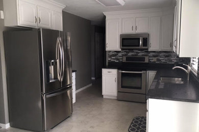 Mid-sized transitional l-shaped kitchen photo in San Diego with a double-bowl sink, raised-panel cabinets, white cabinets, soapstone countertops, gray backsplash, matchstick tile backsplash, stainless steel appliances and no island
