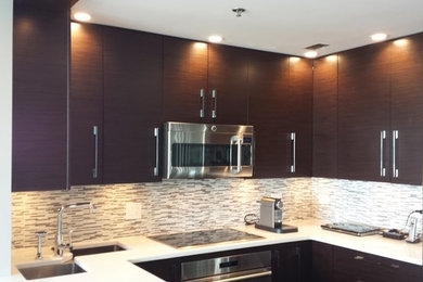 This is an example of a small contemporary u-shaped eat-in kitchen in Chicago with an undermount sink, flat-panel cabinets, dark wood cabinets, solid surface benchtops, white splashback, matchstick tile splashback, stainless steel appliances and with island.