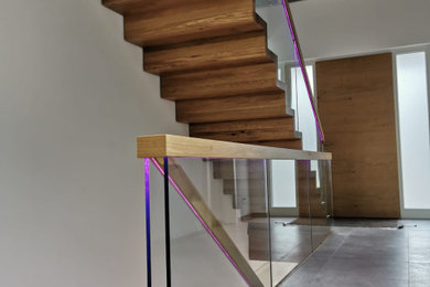 Foto de escalera recta moderna extra grande con escalones de madera, contrahuellas de madera, barandilla de vidrio y ladrillo