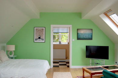 Medium sized modern bedroom in West Midlands with green walls, beige floors, a feature wall and laminate floors.