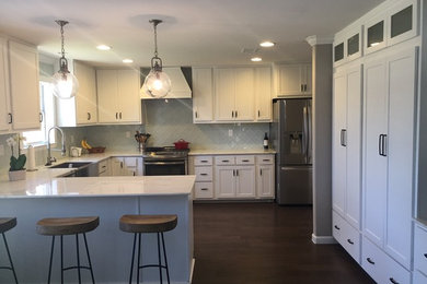 Example of a large transitional u-shaped dark wood floor open concept kitchen design in Dallas with a farmhouse sink, shaker cabinets, white cabinets, quartz countertops, green backsplash, stainless steel appliances and an island