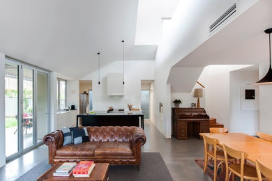 Mid-sized contemporary open concept living room in Sydney with white walls, concrete floors, a standard fireplace, a plaster fireplace surround and a wall-mounted tv.