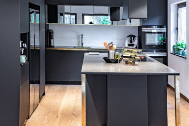 Offene, Mittelgroße Moderne Küchenbar mit Mineralwerkstoff-Arbeitsplatte, schwarzen Elektrogeräten, braunem Holzboden und Kücheninsel in Berlin