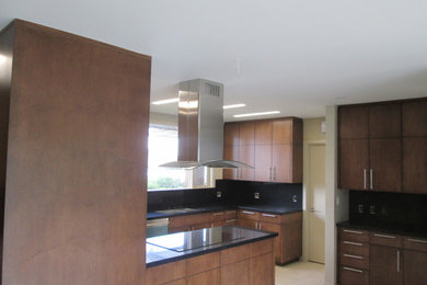 Example of a large minimalist beige floor kitchen design in Los Angeles with a double-bowl sink, quartzite countertops, black backsplash, an island and black countertops