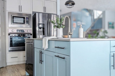 Example of a mid-sized transitional eat-in kitchen design in Edmonton with a double-bowl sink, shaker cabinets, blue cabinets, quartz countertops, white backsplash, subway tile backsplash, black appliances, an island and gray countertops