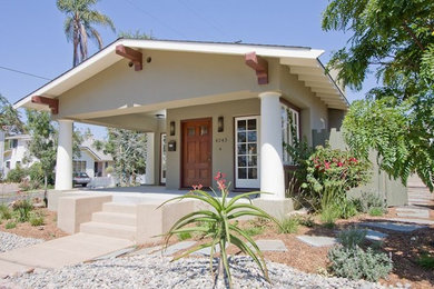 Large traditional one-storey stucco beige house exterior in San Diego with a gable roof and a shingle roof.