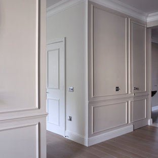 Idéer för en stor klassisk hall, med vita väggar och ljust trägolv