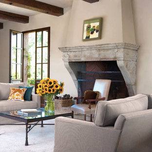 Diseño de salón para visitas cerrado, mediterráneo, grande, sin televisor, con paredes beige, moqueta, chimenea tradicional, marco de chimenea de piedra y suelo blanco