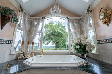 Large elegant master beige tile and marble tile marble floor and beige floor drop-in bathtub photo in New York with beige walls, marble countertops and green countertops