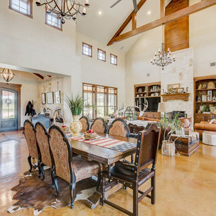 Cette image montre une salle à manger ouverte sur le salon sud-ouest américain avec un mur blanc, béton au sol et un sol marron.