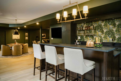 Large light wood floor and brown floor home bar photo in Philadelphia with a drop-in sink, recessed-panel cabinets, green cabinets, granite countertops and black countertops