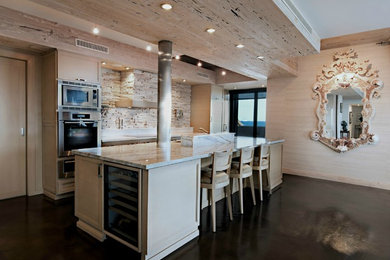 Inspiration for a mid-sized transitional galley concrete floor and brown floor open concept kitchen remodel in Miami with an undermount sink, recessed-panel cabinets, light wood cabinets, limestone countertops, beige backsplash, limestone backsplash, stainless steel appliances and an island