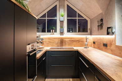 Moderne Schmale Küche mit schwarzen Schränken, Arbeitsplatte aus Holz, Küchenrückwand in Braun, Rückwand aus Holz, hellem Holzboden und brauner Arbeitsplatte in Dortmund