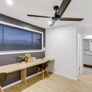 サンシャインコーストの中サイズのモダンスタイルのおしゃれな書斎 (黒い壁、ラミネートの床、造り付け机) の写真