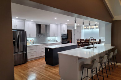 Foto de cocina comedor tradicional renovada grande con fregadero de un seno, armarios con paneles empotrados, puertas de armario blancas, encimera de cuarzo compacto, salpicadero azul, salpicadero de azulejos de vidrio, electrodomésticos de acero inoxidable, suelo de madera en tonos medios, una isla, suelo marrón y encimeras blancas